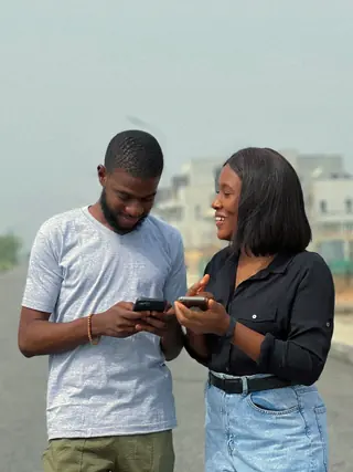 Two friends looking at their phones in the street.